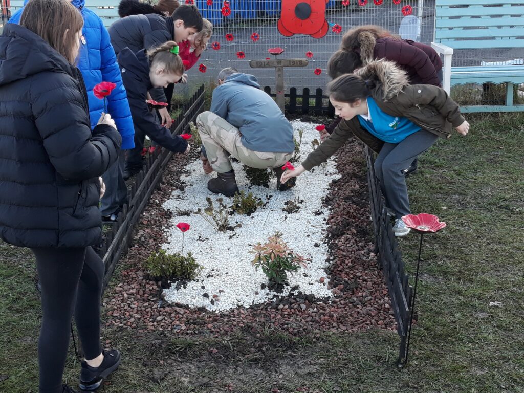 Kids lay poppies as part of a Walking with the Wounded project 