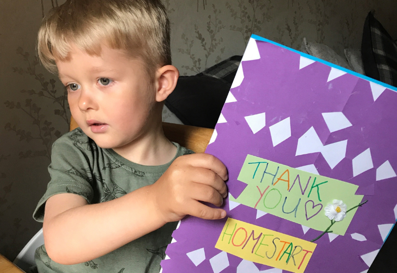 Boy holding up a thank you card from Homestart Norfolk
